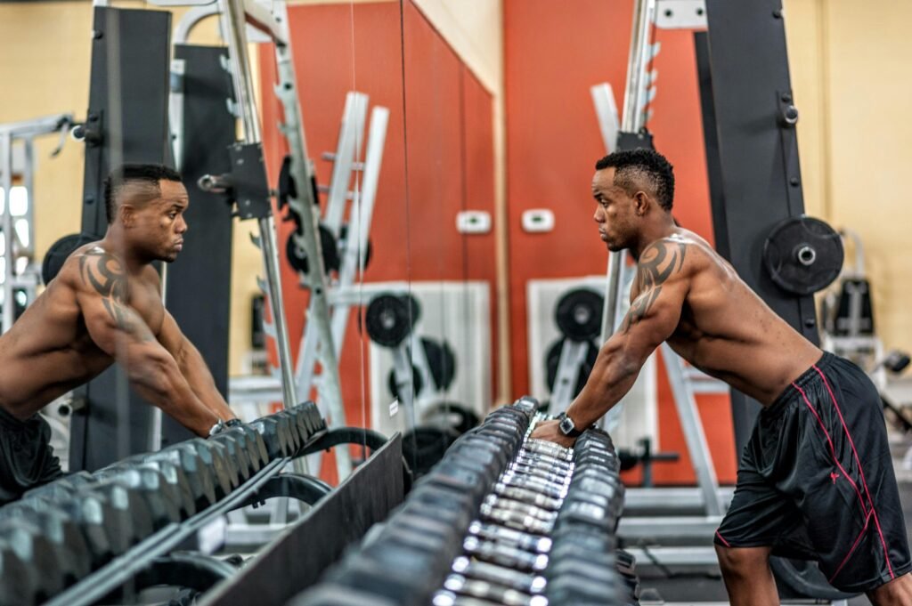 pexels-photo-1144864-1144864 Muscular man exercising with dumbbells in gym, emphasizing strength and fitness.